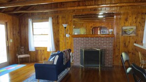 A wooden interior with a fireplace, a blue sofa, and a dining area. - Cabin with 150 ft of beach front and amazing sunsets and sunrises! (Caseville)