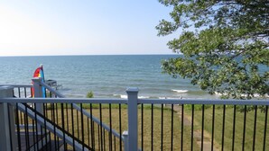 A balcony with a view of the sea, a flag, and a railing. - Cabin with 150 ft of beach front and amazing sunsets and sunrises! (Caseville)