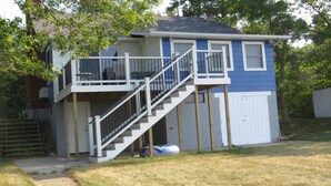 A two-story house with a balcony and a staircase leading to the upper floor. - Cabin with 150 ft of beach front and amazing sunsets and sunrises! (Caseville)