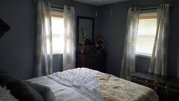 Ein Schlafzimmer mit Bett, Kommode, Globus und Vorhängen.