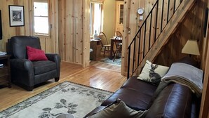 A wooden interior with a sofa, a chair, a rug, and a staircase.