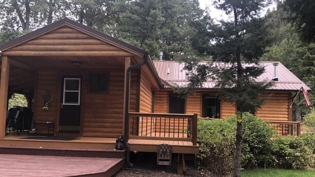 A wooden cabin with a porch and a small deck.