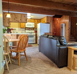 Un intérieur de chalet chaleureux comprenant un coin repas, une cuisine et un canapé en cuir.