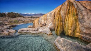 A natural landscape with a clear river, rocky formations, and distant mountains.