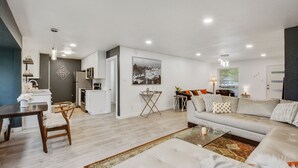 A modern living room with a sofa, coffee table, and dining area. - Just updated,with putting green. 5mi 2 Airpt&Dwtn. Great for family & business.  (Austin)