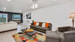 A modern living room with a sofa, armchairs, a coffee table, and a rug. - Just updated,with putting green. 5mi 2 Airpt&Dwtn. Great for family & business.  (Austin)
