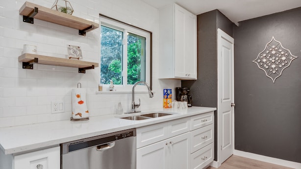 A modern kitchen with white cabinetry, a built-in dishwasher, and a window with a view of greenery. - Just updated,with putting green. 5mi 2 Airpt&Dwtn. Great for family & business.  (Austin)