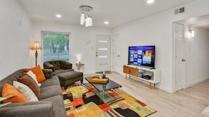 A modern living room with a sofa, coffee table, TV, and decorative items. - Just updated,with putting green. 5mi 2 Airpt&Dwtn. Great for family & business.  (Austin)