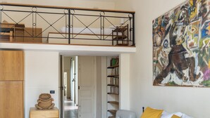 A bedroom with a loft bed, a wooden wardrobe, a bookshelf, and a colorful abstract painting. - Maiorani Family Apartment by Wonderful Italy (Napoli)