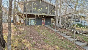 A two-story house with a balcony, surrounded by trees and a grassy area. - Lake Tillery- Beautiful sunrises, large screened porch, and newly renovated home (Norwood)