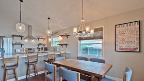A modern kitchen with wooden bar stools, a large wooden dining table, and pendant lighting. - Lake Tillery- Beautiful sunrises, large screened porch, and newly renovated home (Norwood)