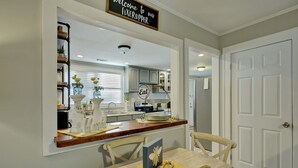 A kitchen with a wooden countertop, a dining table with chairs, and a sign that reads "Welcome to our Fixupper." - "Bee Haven" Cottage Retreat Near Colonial Williamsburg (Gloucester)