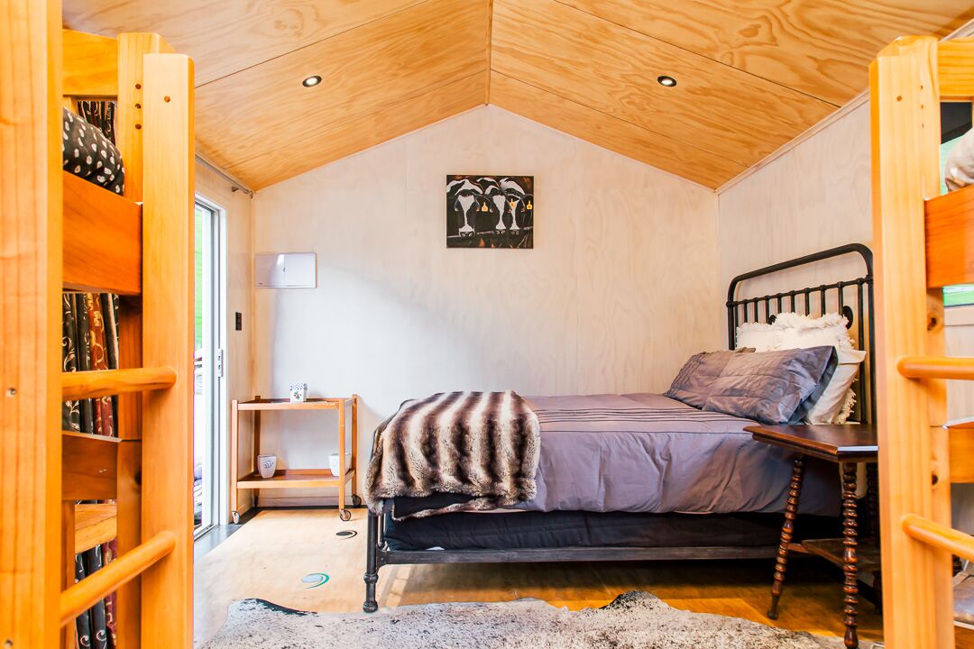 Une chambre confortable avec un plafond en pente, un lit recouvert d’une couverture à motifs, une table de chevet et une œuvre d’art accrochée au mur.