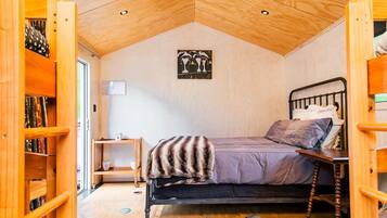 Une chambre confortable avec un plafond en pente, un lit recouvert d’une couverture à motifs, une table de chevet et une œuvre d’art accrochée au mur.