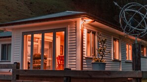 Et hus med store vinduer, en terrasse og en potteplante.