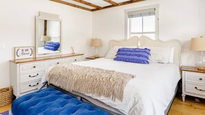 Une chambre à coucher avec un lit, deux tables de chevet, un miroir, une fenêtre et un plafond en bois.
