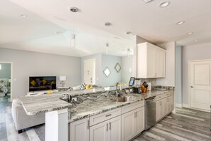 A modern kitchen with a granite countertop, stainless steel appliances, and white cabinetry.