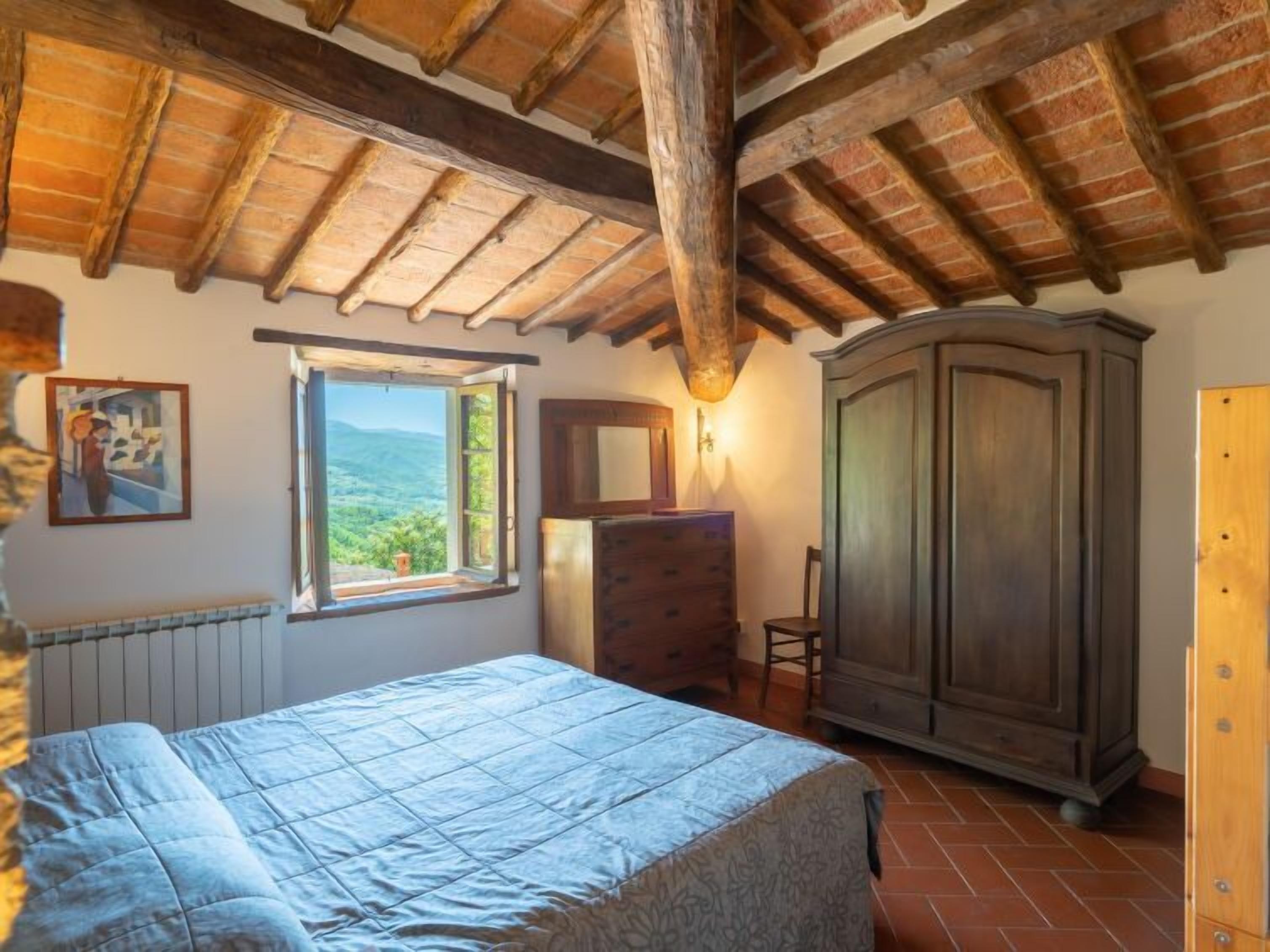 Ein Schlafzimmer mit Holzboden, einem großen Fenster mit Aussicht, einem Bett, einem Schminktisch und einem Kleiderschrank.