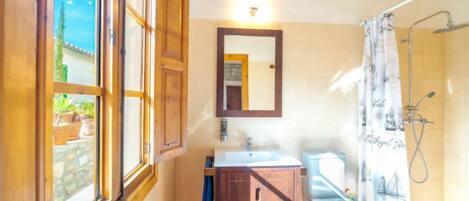 A bathroom with a wooden cabinet, a sink, a mirror, and a shower curtain.