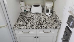 A compact kitchenette with white cabinets, a toaster, a coffee maker, and a small countertop. - Sea Mist 51301 (Myrtle Beach)
