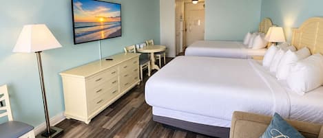 Habitación de hotel con cama, escritorio, silla, lámpara y una pintura de un atardecer.