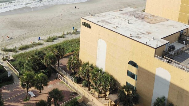 A coastal hotel with a beach view, a parking area, and a building with a flat roof. - Sea Mist 51301 (Myrtle Beach)