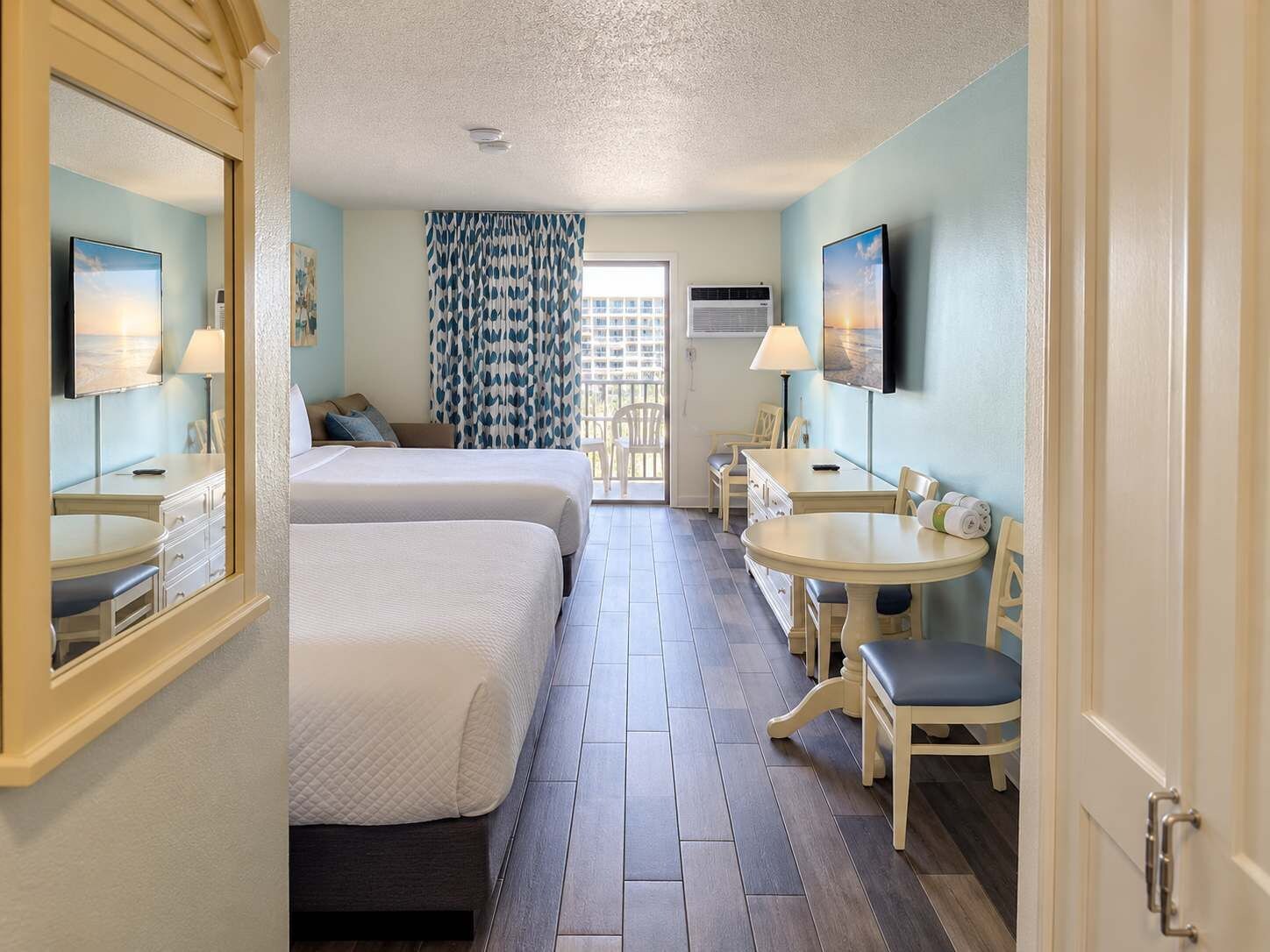 Une chambre d’hôtel avec deux lits, un coin repas et une télévision.
