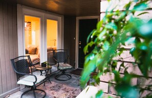 Relax in a serene outdoor seating area with a table and chairs, surrounded by lush greenery and a charming fence.