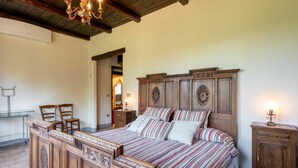 A bedroom with a wooden bed, a chandelier, and a nightstand. - Stunning private villa for 8 people with private pool, WIFI, A/C, TV and terrace (Asti)