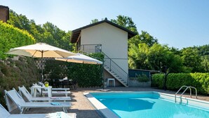 A swimming pool with lounge chairs and umbrellas, a staircase to a second floor, and a brick wall with greenery. - Stunning private villa for 8 people with private pool, WIFI, A/C, TV and terrace (Asti)