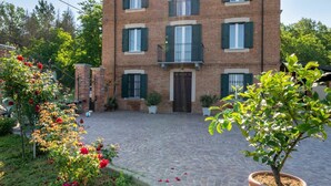 A two-story brick building with a central entrance, multiple windows with shutters, and a paved courtyard. - Stunning private villa for 8 people with private pool, WIFI, A/C, TV and terrace (Asti)