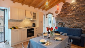 Una cocina acogedora con armarios blancos, una pared de piedra y un comedor con una mesa para cuatro.