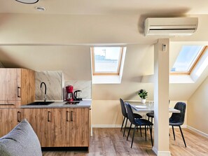 Une cuisine de taille réduite, avec un meuble en bois, un évier, une machine à café rouge et une fenêtre.