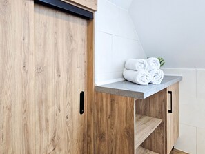 A wooden cabinet with a marble countertop and a towel stack.