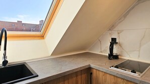Una cuina moderna amb un fanal, armaris de fusta i una cafetera.