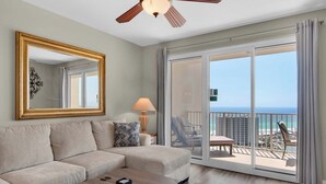 Ein geräumiges Wohnzimmer mit einer großen Couch, einem Couchtisch und einem Balkon mit Meerblick.