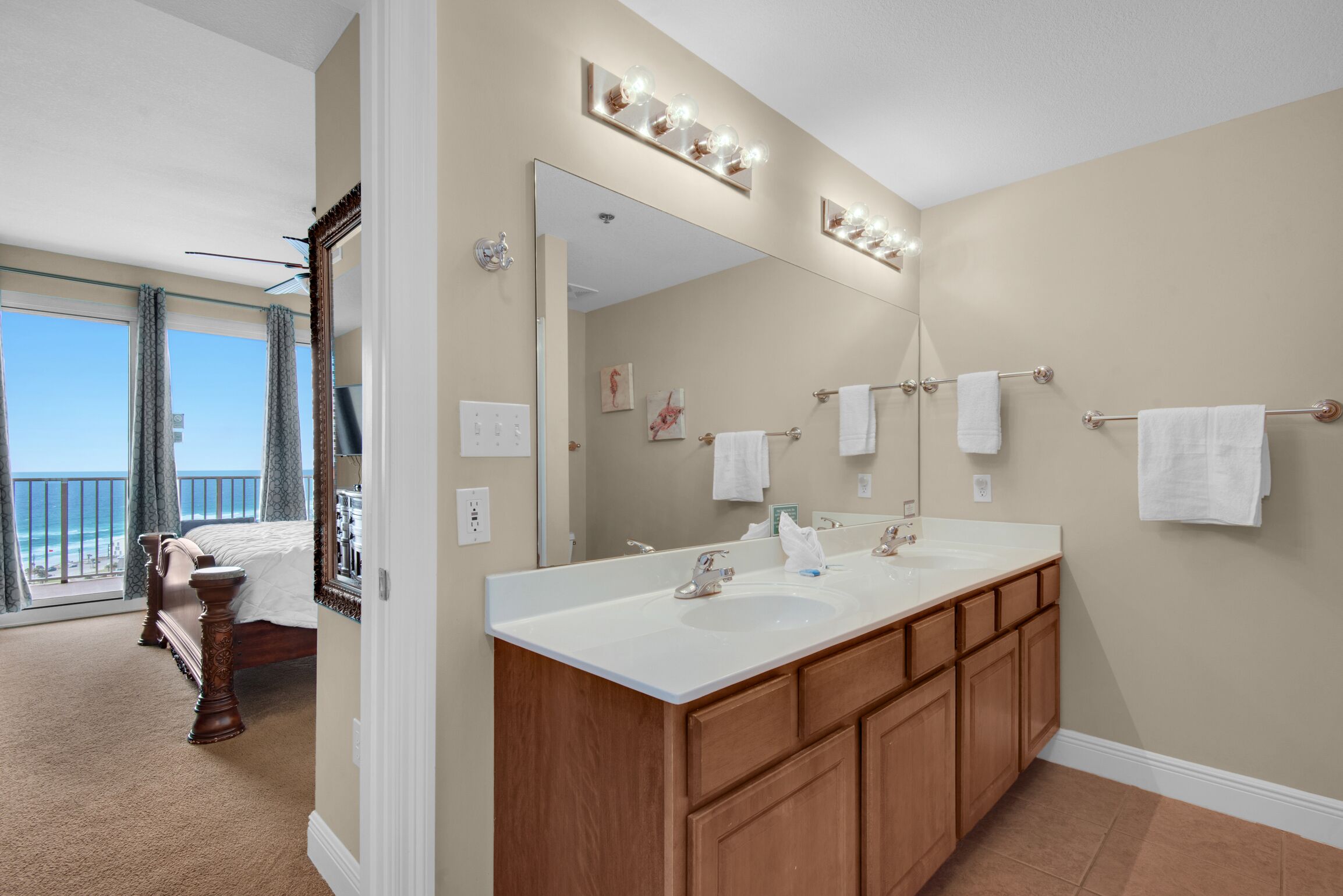 A hotel bathroom with a double sink, vanity, and a large mirror.