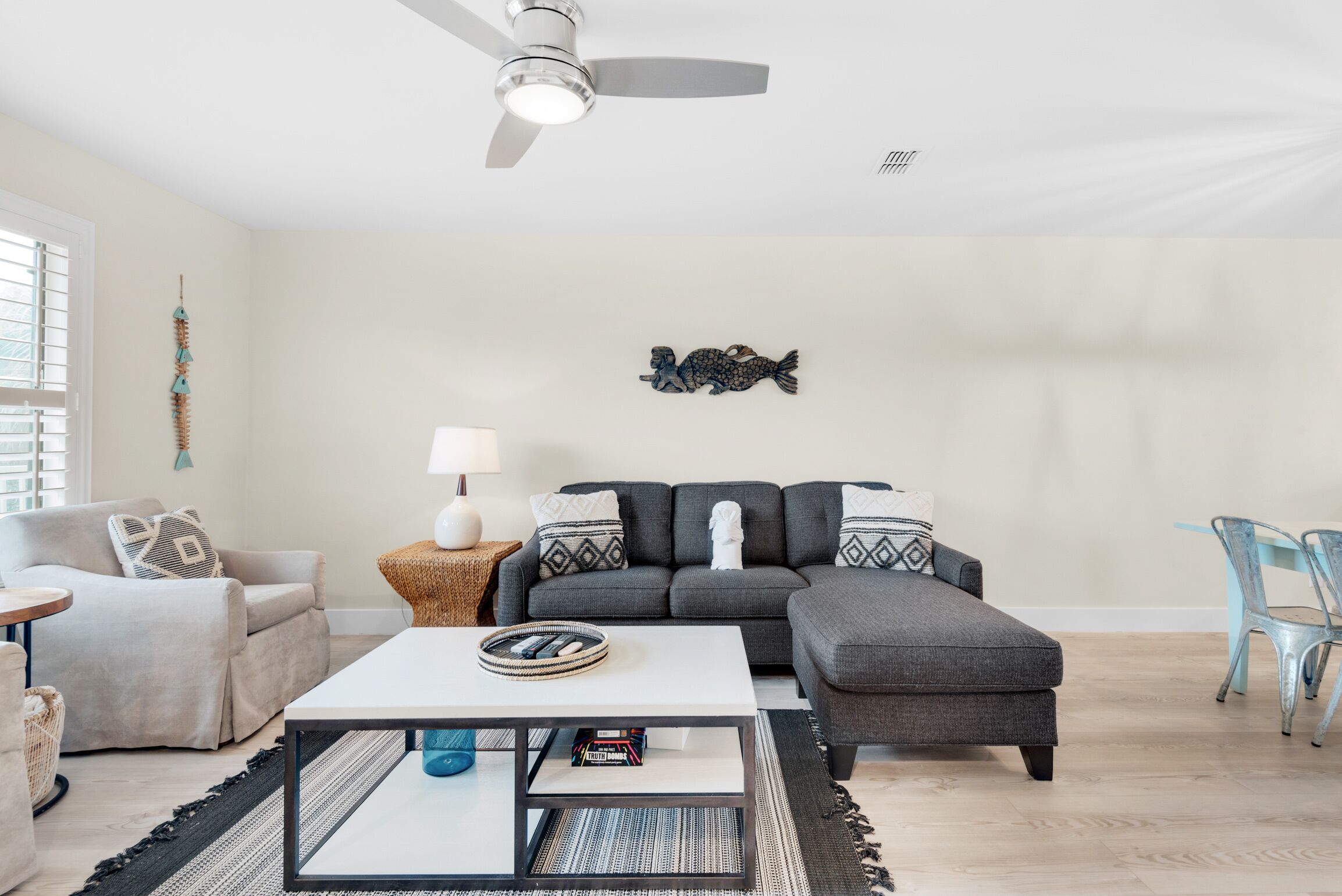 A modern living room with a grey sofa, a white coffee table, and a ceiling fan.