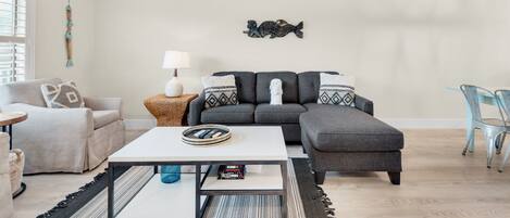 A modern living room with a grey sofa, a white coffee table, and a ceiling fan.