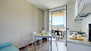 Una cocina moderna con comedor, un balcón con vistas y un sofá azul.