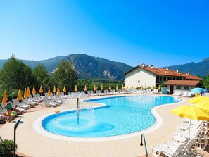 Ein Poolbereich mit Liegestühlen und Sonnenschirmen, umgeben von Bergen.