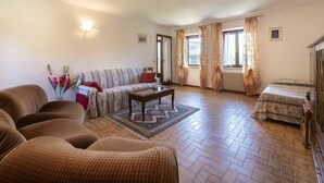A cozy living room with a sofa, armchairs, a coffee table, and a radiator. - Beautiful apartment in villa for 6 guests with TV and patio (San Daniele Del Friuli)