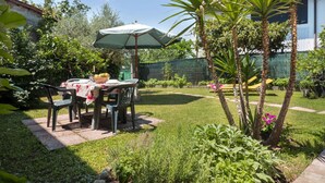 A patio with a table and chairs, surrounded by lush greenery and a fence. - Beautiful apartment in villa for 6 guests with TV and patio (San Daniele Del Friuli)