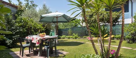 Enjoy al fresco dining in a serene outdoor setting with a table, chairs, and lush greenery.
