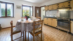 A dining area with a round table, chairs, and a window with curtains. - Beautiful apartment in villa for 6 guests with TV and patio (San Daniele Del Friuli)