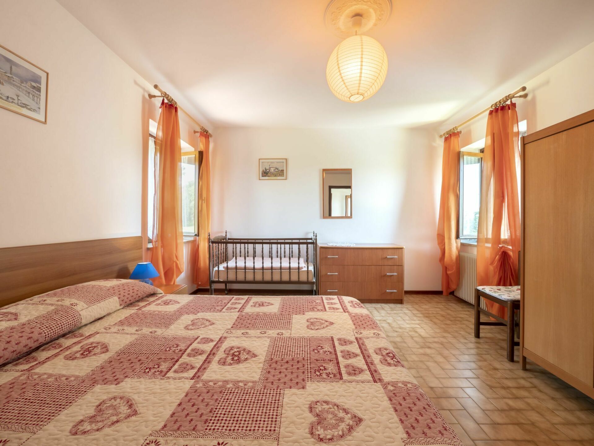 Ein Schlafzimmer mit einem Bett, einem Schminktisch, einem Sessel, einem Spiegel und einer Pendelleuchte.