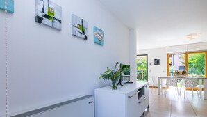 Een moderne keuken met witte kasten, een centraal eiland met een vaas groen en kunstwerken aan de muur.