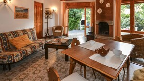 A cozy living room with a wooden ceiling, a sofa, a dining table, and a fireplace. - Beautiful apartment for 7 people with A/C, TV, terrace and pets allowed (Lignano Sabbiadoro)