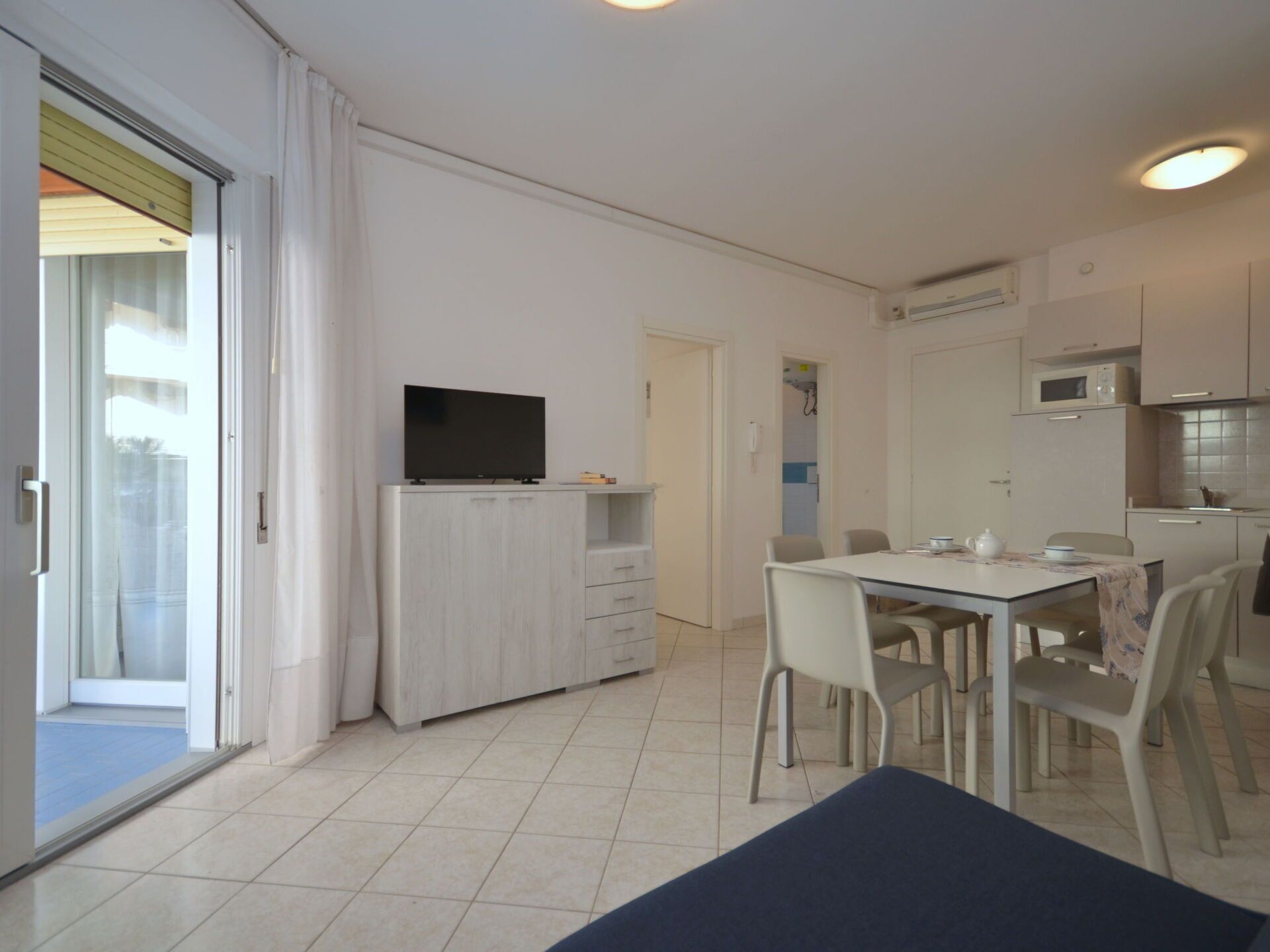 Una cocina moderna con armarios blancos, un microondas y un televisor de pantalla plana sobre un mueble.