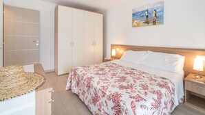 A bedroom with a bed, nightstands, a wardrobe, and a painting on the wall. - Cosy apartment for 6 guests with WIFI, A/C, TV and balcony (Lignano Sabbiadoro)